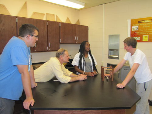Andrew Hubner of Shoreham-Wading River High School, physics teacher Andrew Kolchin, Asia McElroy from Riverhead High School and former Riverhead High School student Phil Becker of Bay Shore do some experiments with Newtown's Cradle Friday at BOCES' new Regional STEM high school in Bellport. (Credit: Tim Gannon)