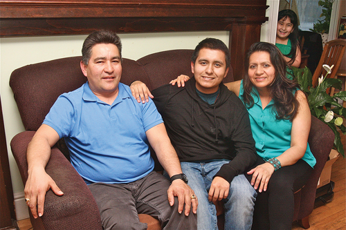 Riverhead High School’s Class of 2014 valedictorian, Ceaser Chabla-Sarmiento, 18, with his parents, Cesar and Maurita Chabla, and sister Kiara, 8, in the background. Ceaser’s parents emigrated from Ecuador to the U.S. and the family lived in Hampton Bays before moving to Flanders. (Credit: Barbaraellen Koch)