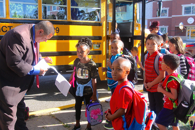 Principal Thomas Payton helps first grader Aubrey Evans find what teacher and classroom she is in.