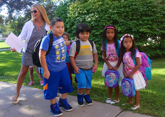 Reading teacher Corrine Arrasate helps children off the bus.