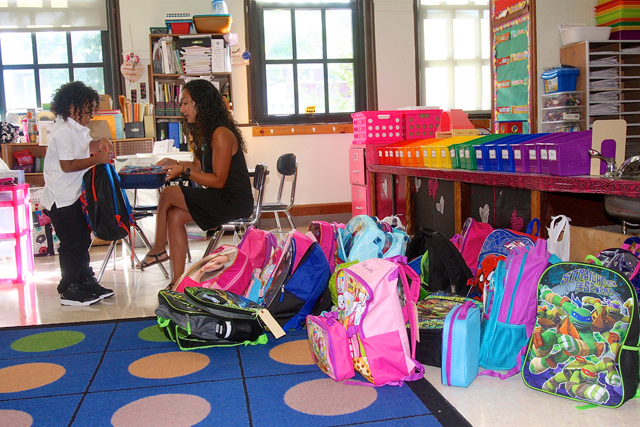 Teacher asistant Christine Santos hleps student McKinnley Hutchinson put his lunch away.