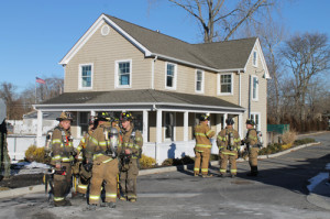 PAUL SQUIRE PHOTO | FIrefighters wait for a LIPA crew to arrive before entering the flooded building.