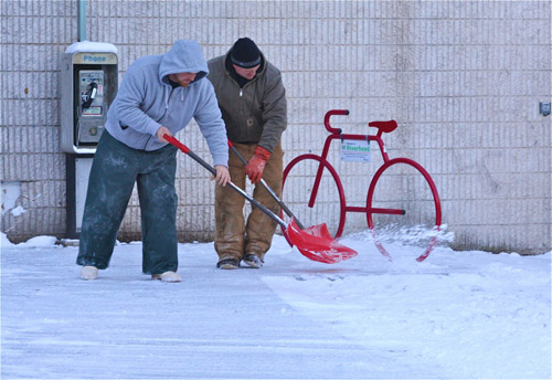BARBARAELLEN KOCH PHOTO | Riverhead building and grounds workers shovel downtown by the River and Roots Community Garden after a storm earlier this winter.
