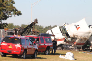 PAUL SQUIRE PHOTO | A towing company employee watches on as the overturned tractor trailer is righted at Exit 73 of the LIE.
