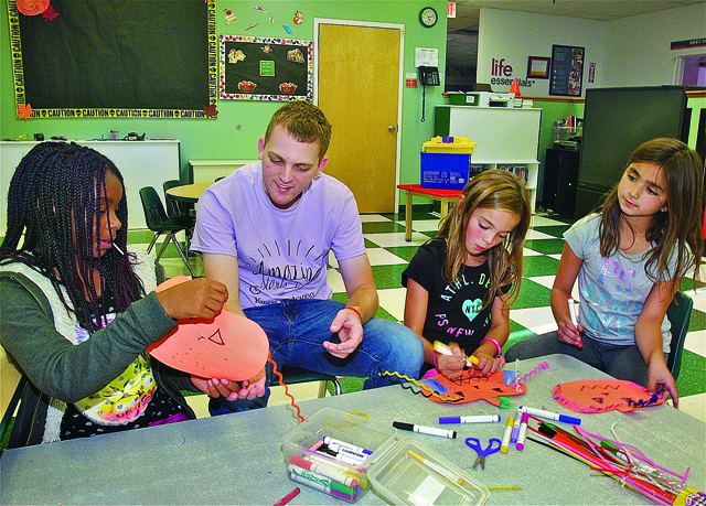 BARBARAELLEN KOCH PHOTOAnthony Mammina with students in after school care (from left) Eunique Trent, 10, Sophia Romeo,9, and Ava Cravotta, 9, making decorations for the bulletin board at Kiddie Academy in Wading River Tuesday afternoon.