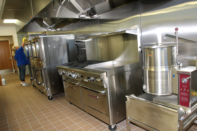 Cafeteria worker Sue Vega cleans the shiny new stainless kitchen equipment.