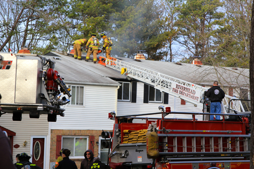 JENNIFER GUSTAVSON PHOTO | Firefighters work on the roof a Calverton home Saturday afternoon.