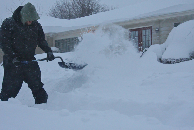 Jake Phillips of Scott Phillips construction of Aquebogue shoveling the sidewalk in front of McLaughlin-Heppner Funeral home at 7:30 p.m. (Credit: Barbaraellen Koch)