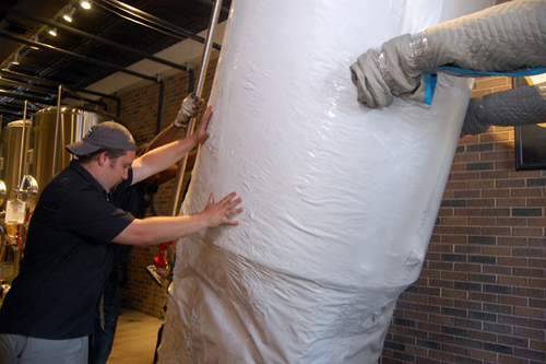 Crooked Ladder assistant beer brewer Stevie Czelatka helps move a new 10′ stainless steel fermentor into the West Main Street tasting room. (Credit: Vera Chinese)