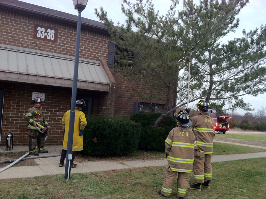 Riverhead firefighters breaking windows in an upper floor window at the Doctors Path Apartments Monday afternoon. (Credit: Michael White)