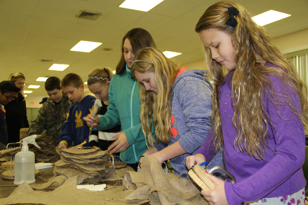Sixth graders Lauren Onufrak,11, Emma Olsen, 11, and Myah Orlowski, 12, prepare burlap disks for Cornell researchers.