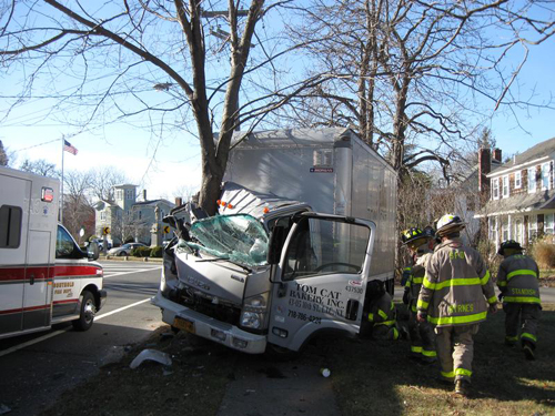 SOUTHOLD FIRE DEPARTMENT COURTESY PHOTO | Firefighters survey the scene where a delivery truck smashed into a tree in Southold Saturday morning.