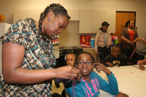 Ms. Fulford shows Stephanie Berkely how to braid a lanyard.