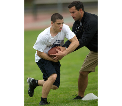 Billy McAllister takes a handoff from offensive coordinator Chris Robinson during Greenport/Mattituck/Southold's mini-camp on Friday at Mattituck High School. (Credit: Garrett Meade)