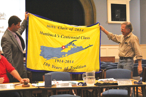 JENNIFER GUSTAVSON PHOTO | Mattituck High School principal Shawn Petretti (left) and school board member Doug Cooper unveil the centennial class’s flag. The 2014 commencement will take place June 21.