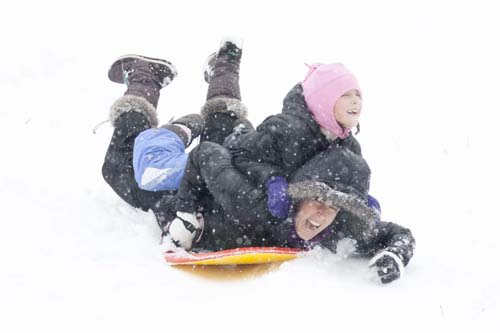 KATHARINE SCHROEDER PHOTO | Seven-year-old Bailey Shannon of Cutchogue hitches a ride atop her mom at the sledding hill in Mattituck.