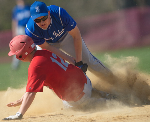 GARRET MEADE PHOTO | Southold's Alex Poliwoda sliding safely under Shelter Island shortstop Hunter Starzee and kicking up a dust cloud.