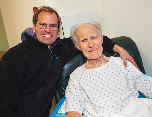 Jeff Heidtmann and the man he rescued, Robert Frey, pose for photos last January, when they were reunited for the first time after Mr. Heidtmann pulled the older man from the icy waters of a canal behind the neighbors’ Southold homes. Mr. Frey has no memory of falling in or being pulled from the canal. (Credit: Paul Squire)