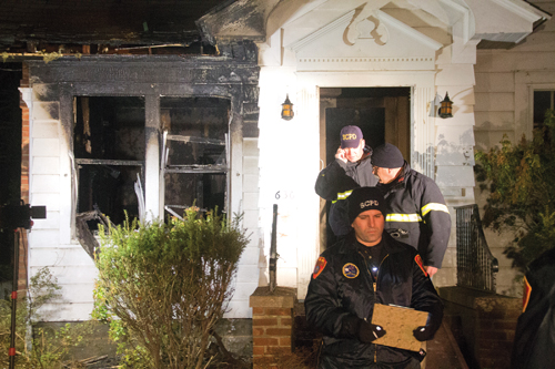Investigators leave the home of Karen Pollack March 5 — the night her husband, Jack, was killed in a house fire. Nearly a year later, she's still working to get back into the house. (Credit: Paul Squire, file)