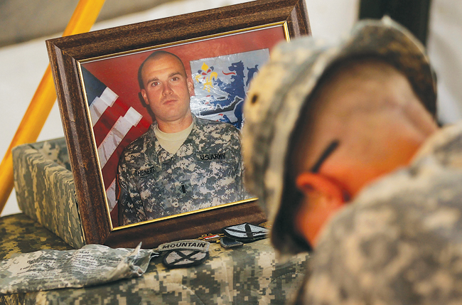 A soldier in the 1-71st Cavalry of the 10th Mountain Division bows during a memorial service for Lt. Joseph Theinert in June 2010 at the patrol base in Belanday, south of Kandahar, Afghanistan. (Credit: Chris Hondros/Getty Images)