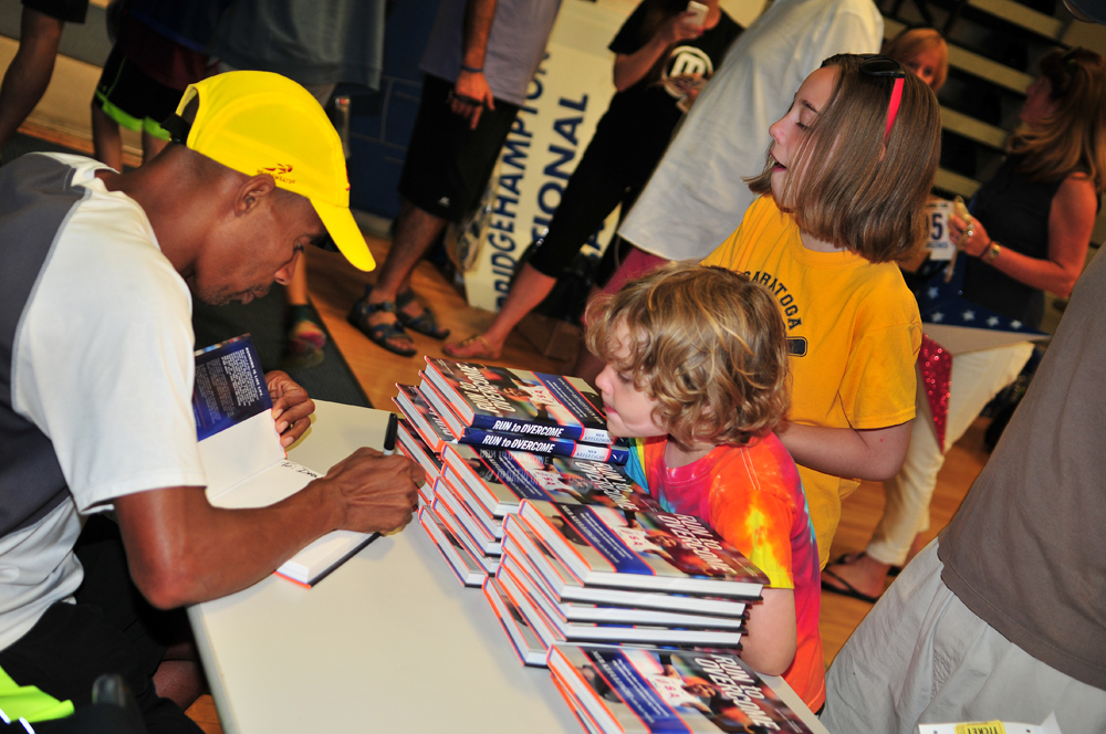 Boston Marathon winner Meb Keflezighi autographs copies of his book prior to the race. (Credit: Bill Landon)