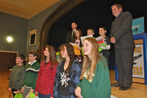 BARBARAELLEN KOCH PHOTO Supesrvisor Scott Russell (far left) with the "Weather in 2040" poster contest winners (front row from left) sixth to eighth grade winners Caleb Foley, Dane Reda, Jillian Orr, Cassidy Mullin, Dorothy Condon and not pictured Gabrielle Wahlers. Back row third grade winners (from left) Leah Weir, Thomas McGunnigle and Michael Garrett with Optimum emcee Lou Brogno Wednesday afternoon at Mattituck High School.